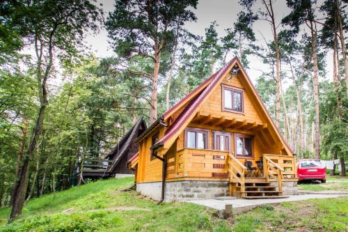 a log cabin in the woods with a car parked in front at Ośrodek Wypoczynkowy AKWA Marina in Nysa