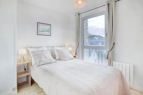 une chambre blanche avec un lit et une fenêtre dans l'établissement Le Sterne, à Pléneuf-Val-André