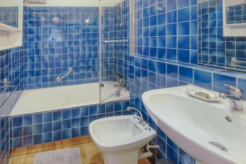 La salle de bains est pourvue de carrelage bleu, de toilettes et d'un lavabo. dans l'établissement Le Sterne, à Pléneuf-Val-André