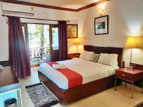 een slaapkamer met een groot bed en een raam bij The Camelot Beach Resort - Baga in Baga
