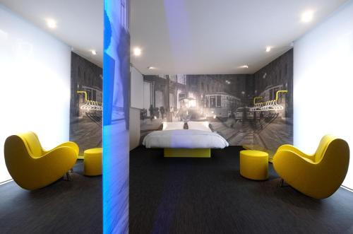 a bedroom with a bed and yellow chairs at The Street Milano Duomo | a Design Boutique Hotel in Milan