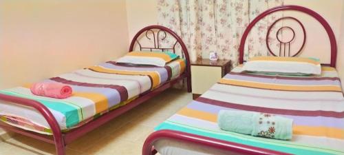 two beds in a small room withskirts at Cahaya Kasih Homestay in Kangar