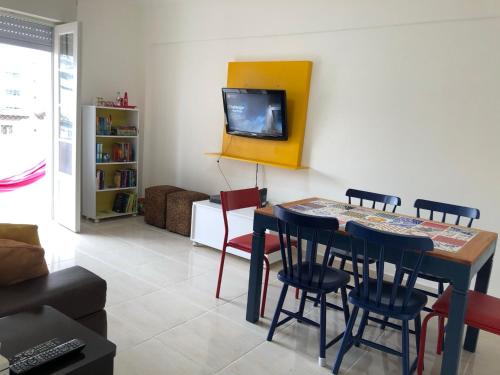 a living room with a table and chairs and a tv at Apto. frente ao mar no Gonzaga - melhor localização! in Santos