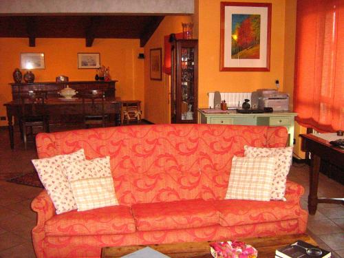 a living room with a red couch with pillows at B&B Casa Dolce Casa in Candelo