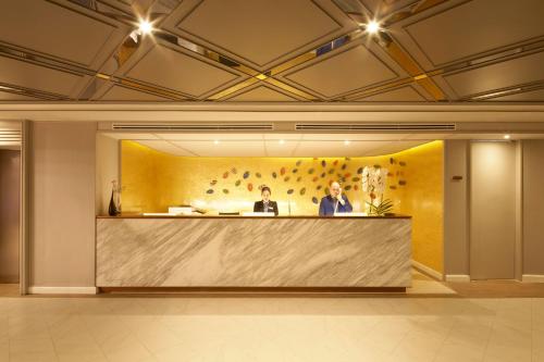 two people sitting at a reception desk in a lobby at The Quarter Ploenchit by UHG in Bangkok