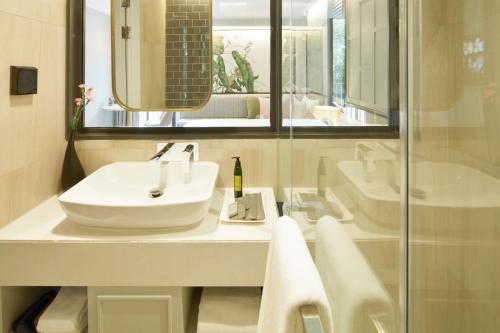 a white bathroom with a sink and a shower at The Quarter Ploenchit by UHG in Bangkok