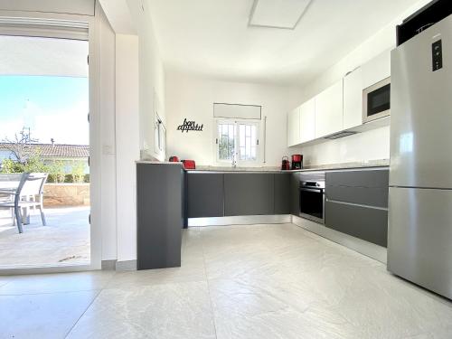 a kitchen with a stainless steel refrigerator and a table at Villa Bouganvilla luxury villa with air-con, & private swimming pool ideal for families in L'Ametlla de Mar