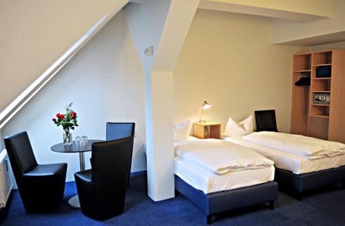 two beds in a room with a table and chairs at Hotel Transit Loft in Berlin