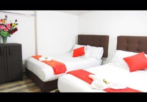 a bedroom with two beds with red and white pillows at Hotel Casa Román in Bogotá