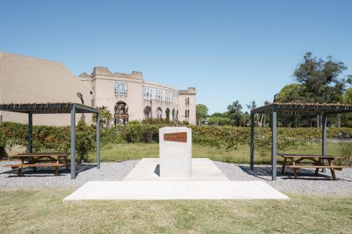 two benches and a monument in front of a building at Taurinas in Colonia del Sacramento