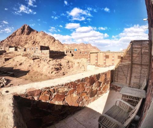 a bench sitting on a wall with a mountain in the background at Sheikh Mousa Bedouin Camp in Saint Catherine