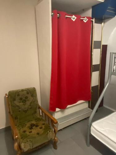 a bedroom with a red shower curtain and a chair at la chambre de Jade in Hirson