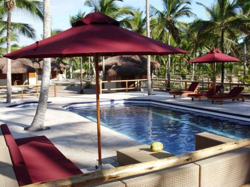 a pool with an umbrella and chairs and an elephant in the background at Kani Boutique Resort in Canavieiras