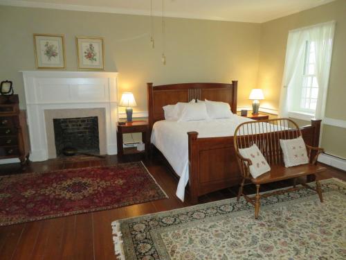 a bedroom with a bed and a chair and a fireplace at Cider House Bed and Breakfast in Waynesboro