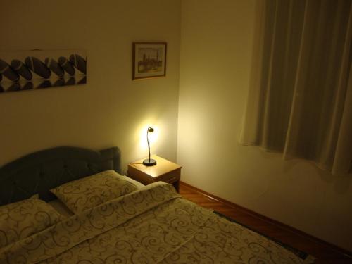 a bedroom with a bed and a lamp on a night stand at Centre Point Apartment in Podgorica