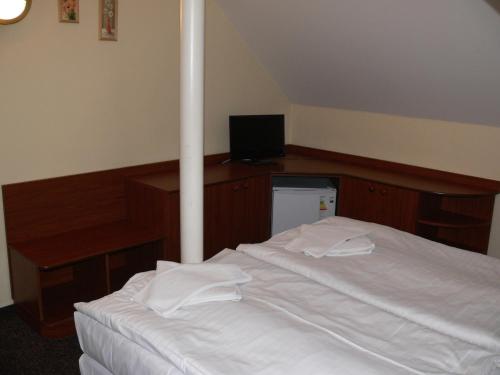 a bedroom with a white bed and a television at Penzion Oaza in Luhačovice