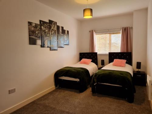 1 dormitorio con 2 camas con sábanas verdes y blancas en Stockton Heights, Warrington, Centrally Located Between Town Centre and Stockton Heath, High Speed Wifi, Cozy Stay, en Warrington