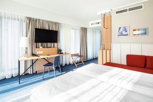 a hotel room with a bed and a desk with a television at Holiday Inn Gdansk - City Centre by IHG in Gdańsk