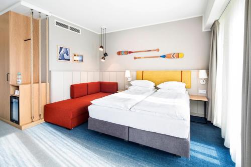 a bedroom with a bed and a red chair at Holiday Inn Gdansk - City Centre by IHG in Gdańsk