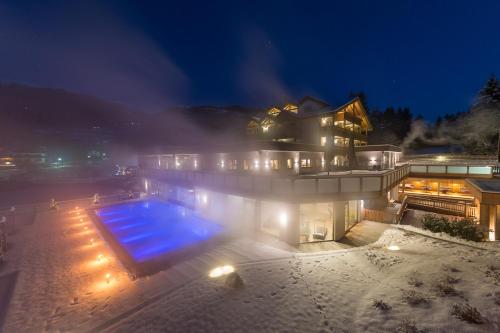 a house with a swimming pool in the snow at night at Hotel Weiher Green Lake in Falzes