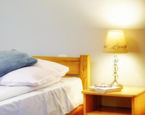 a bed with a lamp and a book on a night stand at DW Pod Jaworami - relaks w SPA - jacuzzi, sauna na wyłączność in Białka Tatrzanska
