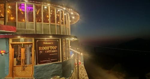 a building with a sign in front of it at night at Rooftop Cottages & Restaurant, Pangot in Nainital
