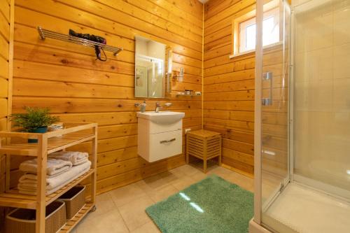 a bathroom with wooden walls and a shower and a sink at Hotel Krutitcy in Sasykino