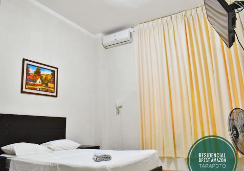 a hotel room with two beds and a curtain at Residencial Brest Amazon Tarapoto in Tarapoto