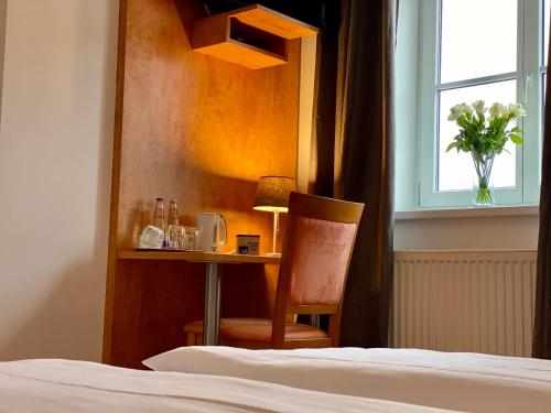a bedroom with a desk and a bed and a chair at Hotel Waitzingers in Landsberg am Lech