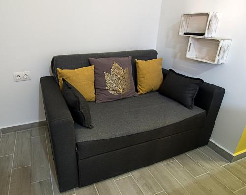 a black couch with pillows on a wall at Nicola's Apartments in Kassiopi