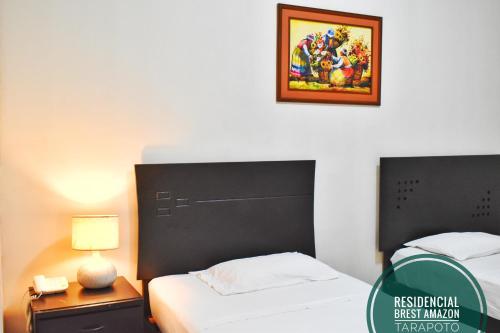 a bedroom with two beds and a picture on the wall at Residencial Brest Amazon Tarapoto in Tarapoto