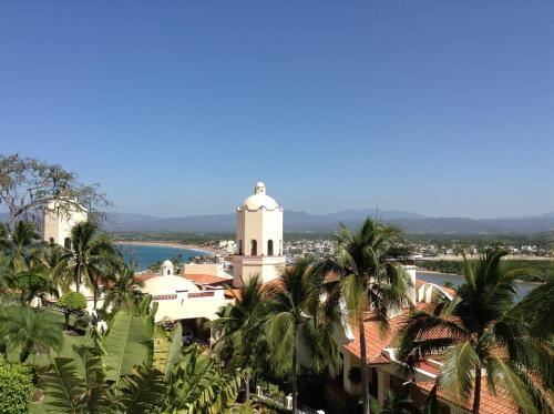 a view of a building with palm trees in the foreground at Grand Isla Navidad Golf & Spa Resort with Marina in Barra de Navidad