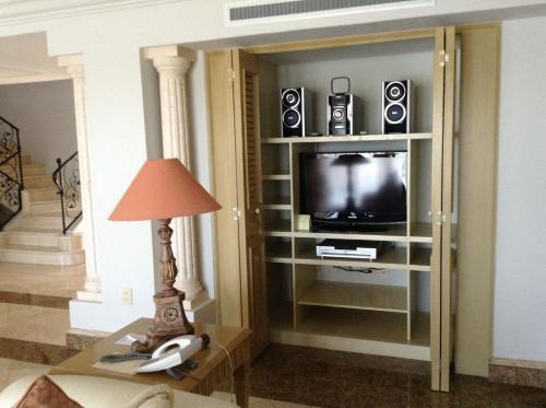 a living room with a tv and a table with a lamp at Grand Isla Navidad Golf & Spa Resort with Marina in Barra de Navidad