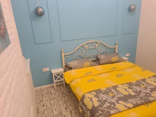 リヴィウにあるStyle Loft Apartmentのベッドルーム1室(黄色のシーツと青い壁のベッド1台付)