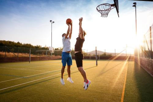 two men jumping to catch a basketball on a tennis court at Apartmány Engadin in Boží Dar