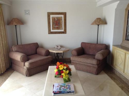 a living room with two chairs and a table with flowers at Grand Isla Navidad Golf & Spa Resort with Marina in Barra de Navidad
