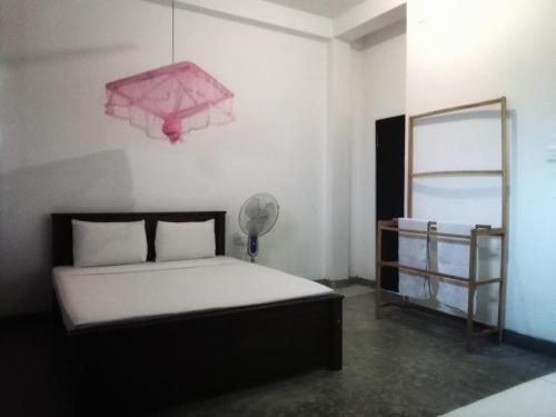 um quarto com uma cama e um candeeiro rosa em The Nest em Tangalle