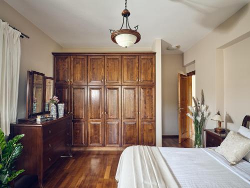 a bedroom with a large wooden wardrobe and a bed at Villa Castelletto heated pool jacuzzi in Kipseli