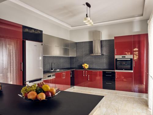 a kitchen with red cabinets and a bowl of fruit on a table at Villa Castelletto heated pool jacuzzi in Kipseli
