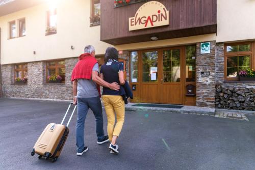 Ein Mann und eine Frau gehen mit einem Koffer in der Unterkunft Apartmány Engadin in Boží Dar