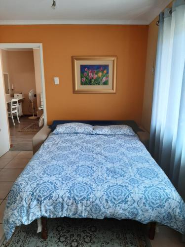 a bedroom with a bed with a blue comforter at Bibi's Place in Swakopmund