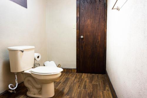 a bathroom with a toilet and a wooden door at Quinta Monasterio in Valle de Guadalupe