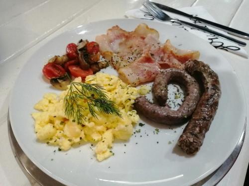 a plate of breakfast food with sausage eggs and tomatoes at Villa Mariss Guesthouse in Kraaifontein