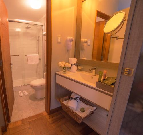 a bathroom with a sink and a toilet and a mirror at Hotel Pasko in Santiago