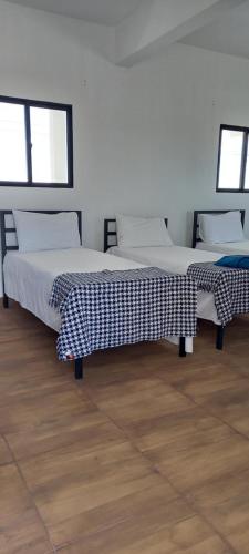 two beds in a room with wooden floors and windows at Flor de Mandacaru Pousada in Boqueirão (1)