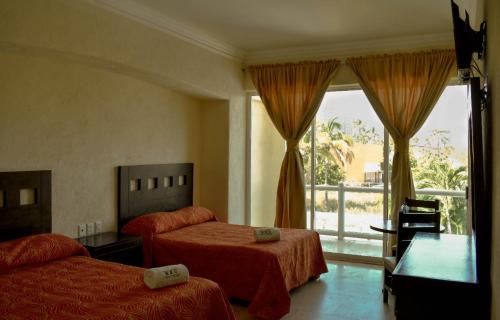 a hotel room with two beds and a balcony at Hotel RRU Diamante in Acapulco