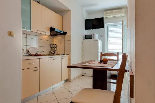 a small kitchen with a wooden table and a chair at Luxury Apartments Tafra in Lokva Rogoznica