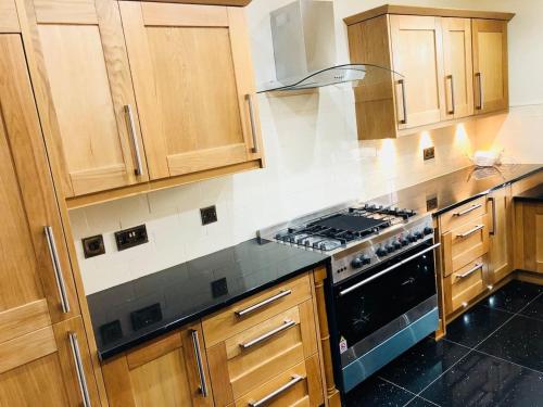 uma cozinha com armários de madeira e um forno com placa de fogão em Beautiful 4-Bed Villa in Glasgow em Glasgow