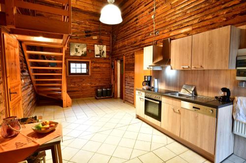 a large kitchen with wooden walls and wooden cabinets at FEWO Wittener Hütte in Langenbach b.K. in Langenbach bei Kirburg