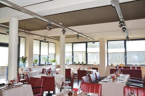 a restaurant with white tables and chairs and windows at Le Presbytère in Differdange
